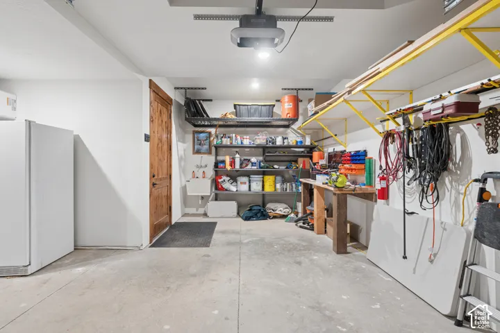 Concrete flooring with a rustic wood-panel door, overhead lighting, and built-in wall shelving