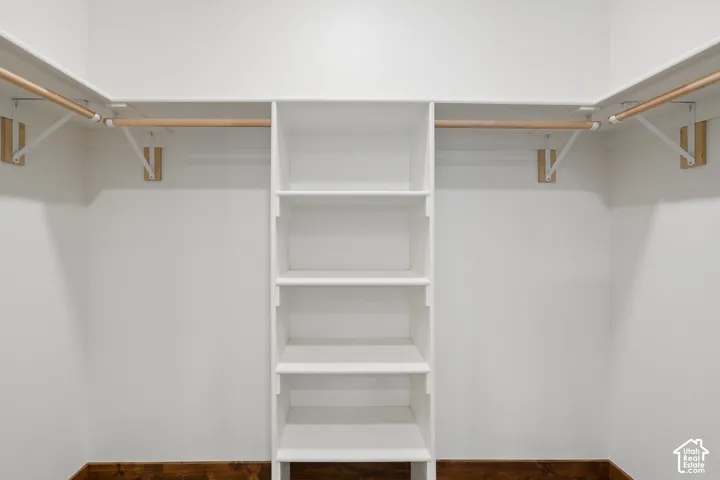 Built-in shelving unit with multiple shelves, dual wooden hanging rods, and contrasting wood-finish flooring