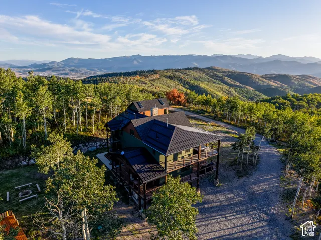 Multi-level property nestled among deciduous trees, featuring a prominent metal roof and multiple covered balconies