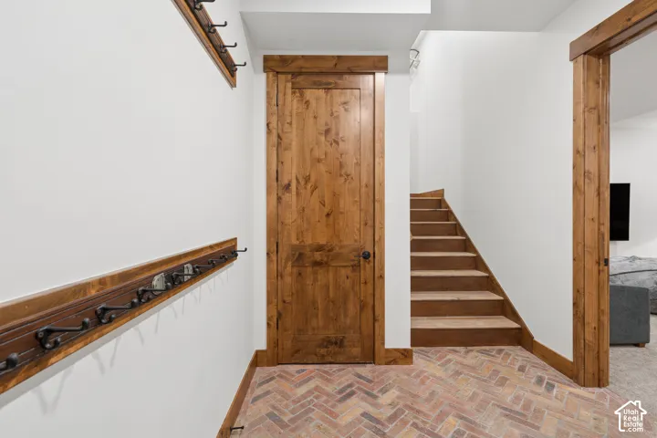 Herringbone brick flooring, wood-finish interior door, wood trim, and wood staircase