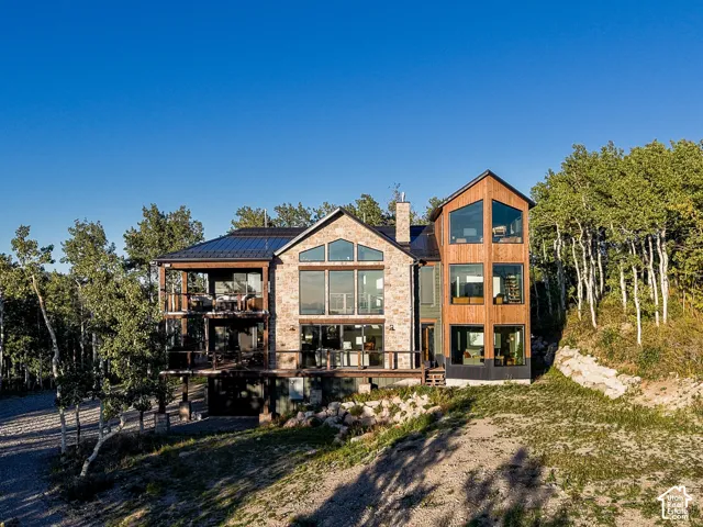 Multi-level contemporary exterior with extensive glazing, stone and wood-clad facades, and multiple balconies