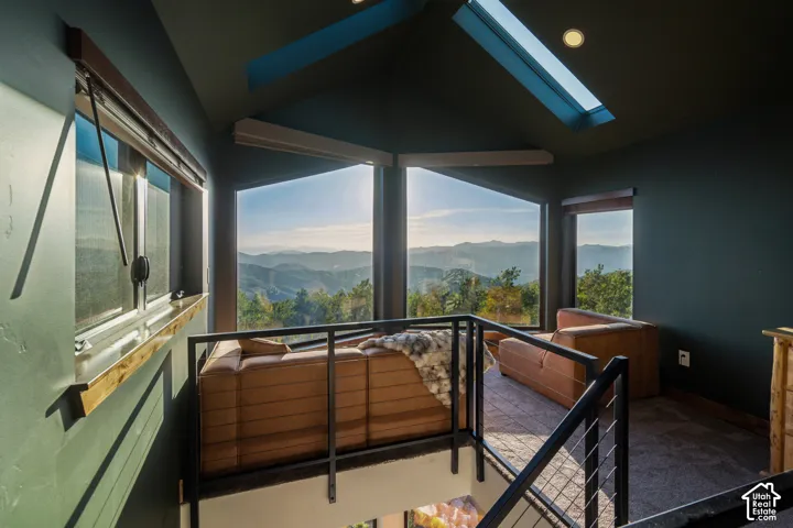 Expansive windows showcasing mountain scenery, vaulted ceiling with skylight, and modern metal railings