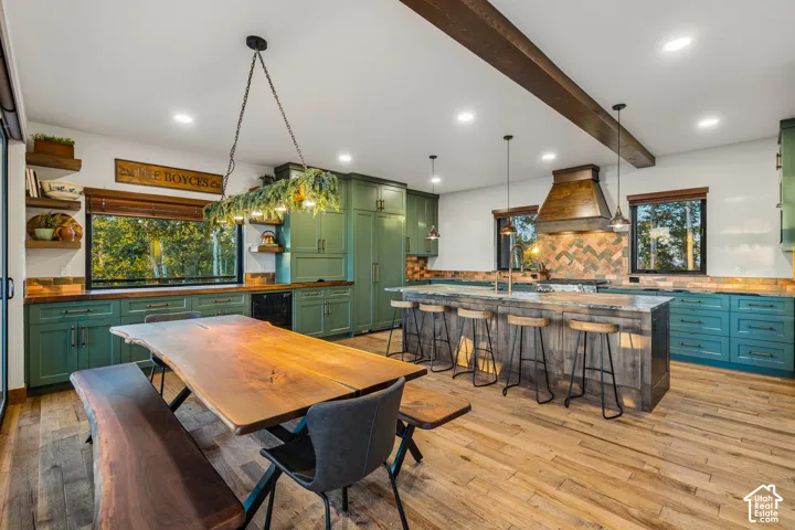 Spacious kitchen featuring a large central island, wood-finish flooring, exposed ceiling beam, and painted cabinetry