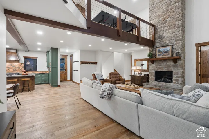 Expansive living area featuring light wood-finish flooring and a stone-clad fireplace