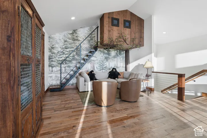 Hardwood flooring throughout, featuring a built-in wooden cabinet with mesh doors, and a metal staircase with open risers