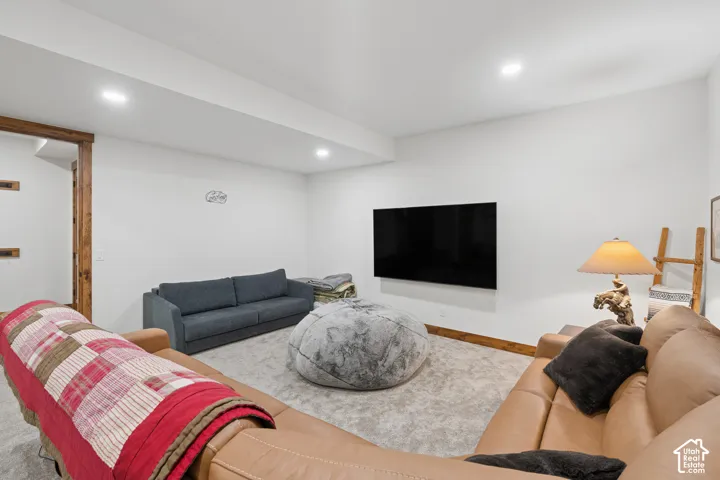 Recessed lighting, wood-finish structural beams, carpeted flooring, and a wall-mounted display space