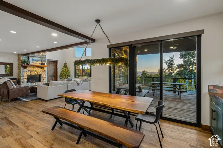 Expansive wood-finish flooring throughout, complemented by exposed ceiling beams and a stone-faced fireplace with a wood mantle