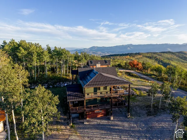 Multi-level exterior with extensive decking, metal roof, and surrounding mature trees