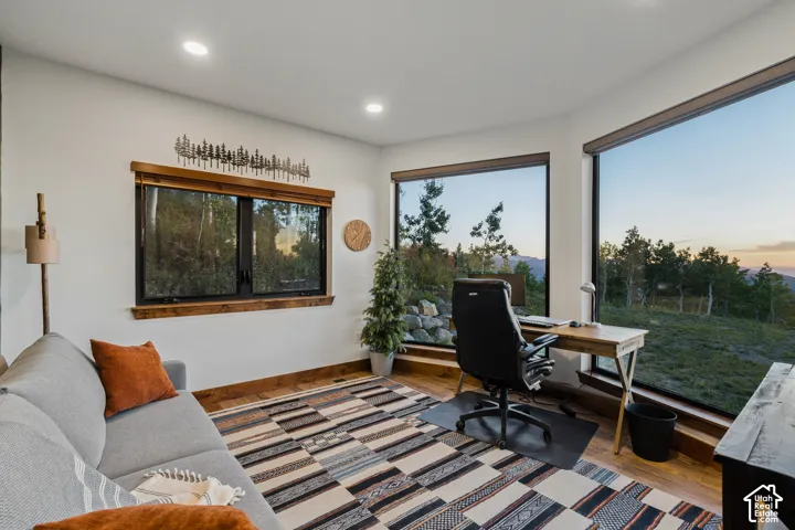 Recessed ceiling lighting, expansive windows with mountain and sky scenery, wood-finish flooring, and natural wood window trim