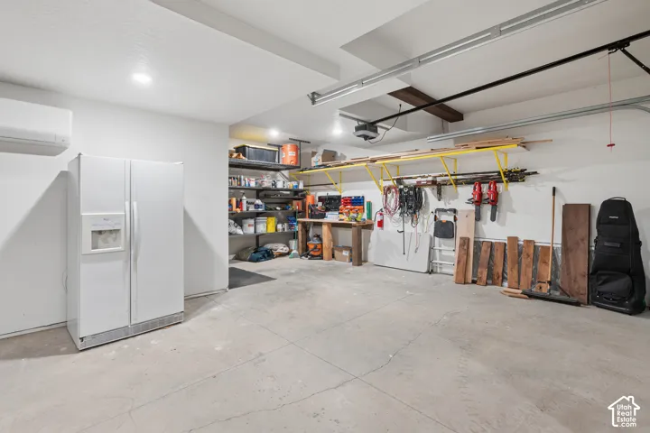 Spacious garage with concrete flooring, wall-mounted shelving, and ceiling-mounted lighting