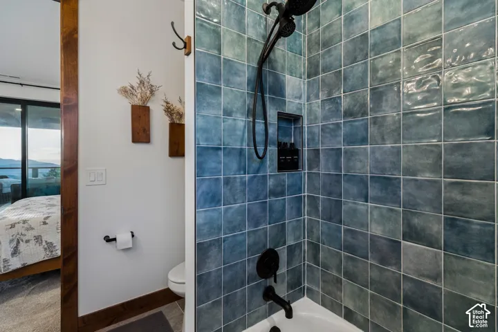 Shower with blue-toned square tiles and a matte black shower head