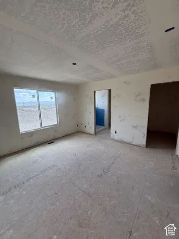 Interior space featuring unfinished drywall, textured ceiling, subflooring, and a single-pane sliding window