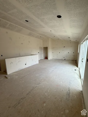 Vaulted ceiling with recessed lighting, integrated wall half-wall, and sliding glass door