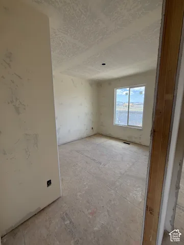 Interior room featuring unfinished walls, subflooring, a textured ceiling, and a window with exterior scenery