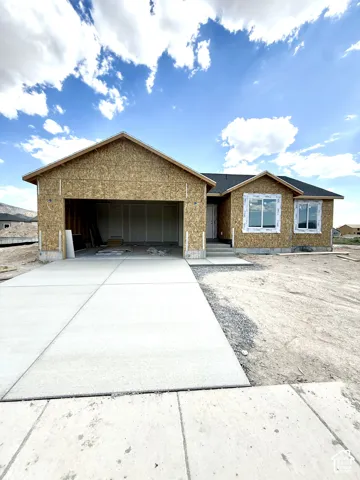 Gable-roof exterior featuring an attached two-car garage, concrete driveway, and installed exterior window frames