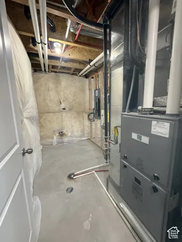 Mechanical area featuring a high-efficiency forced air furnace, exposed structural framing, concrete flooring, and insulated wall barriers