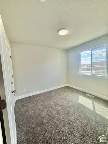 Neutral-toned interior space featuring carpeted flooring, a single-pane sliding window, and a flush-mount circular ceiling fixture