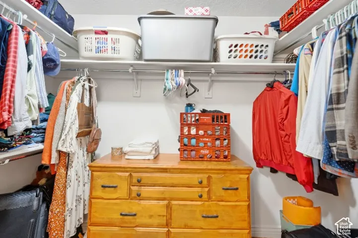 Walk-in closet featuring floor-to-ceiling hanging rods and custom white shelving