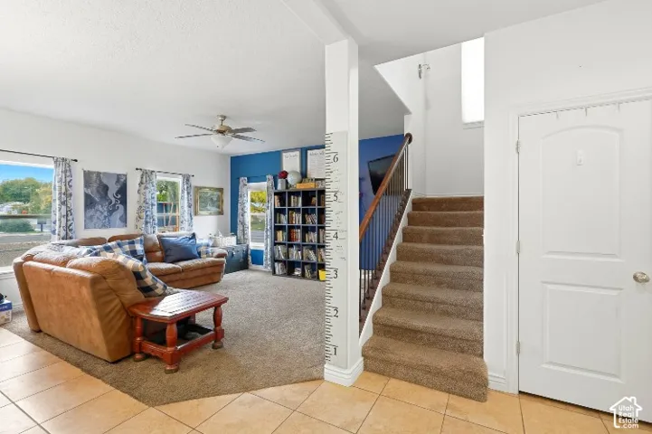 Entryway featuring tile flooring, carpeted staircase with metal balusters, and windows with neutral-toned walls