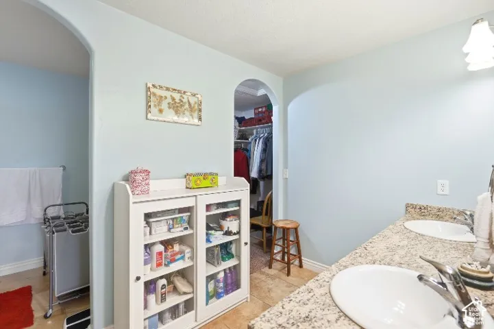 Dual-sink vanity with stone-style countertop and arched doorways