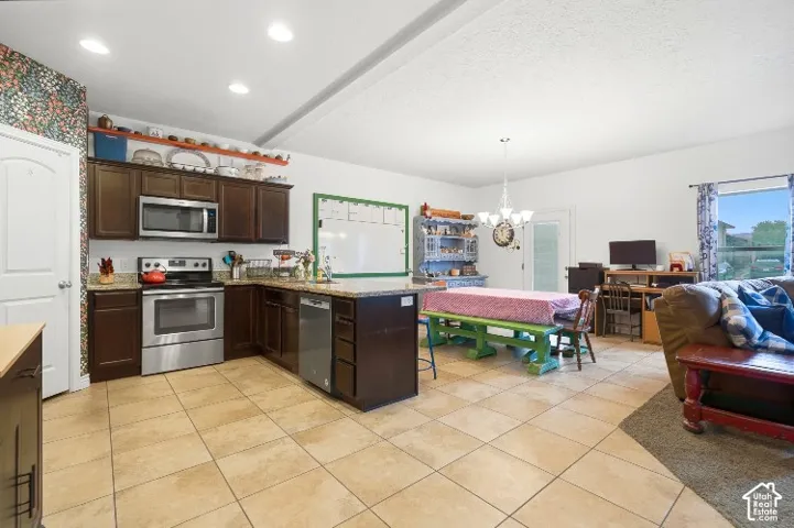 Kitchen featuring dark-toned cabinetry, stone-finish countertops, stainless steel appliances, ceramic tile flooring, and recessed ceiling lighting