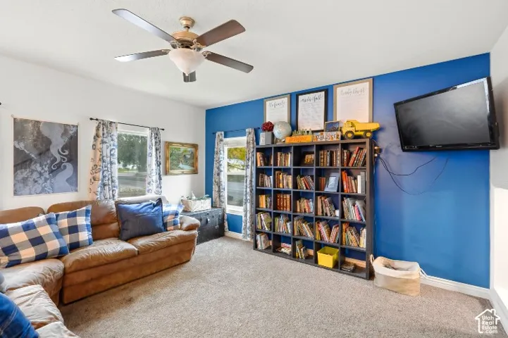 Interior space featuring neutral carpeting, dual windows, and a ceiling fan with integrated lighting