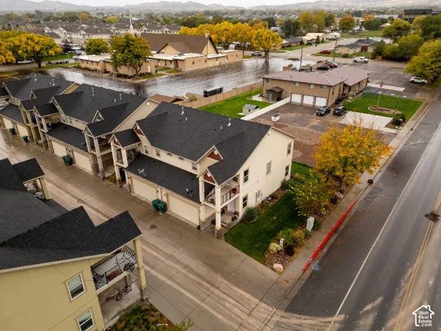 Aerial perspective featuring multi-story residential structures with dark asphalt shingle roofing, attached multi-car garages, and covered balconies