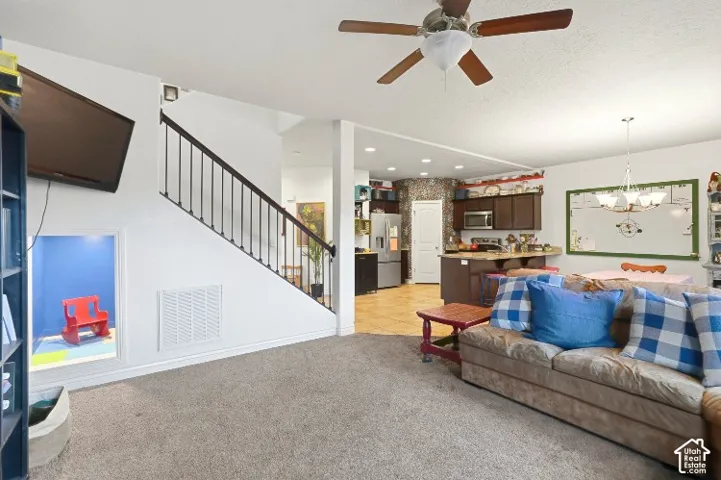 Open-concept interior featuring a recessed wall nook, staircase with dark metal balusters, ceiling fan, and recessed lighting