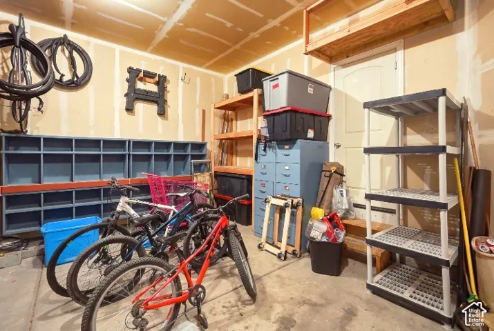 Garage featuring built-in blue storage cubbies, elevated overhead wooden storage shelving, and a paneled pedestrian door