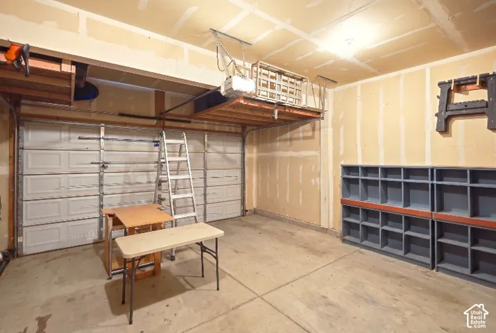 Two-car garage featuring a sectional overhead door, overhead storage platform, and wall-mounted grid shelving
