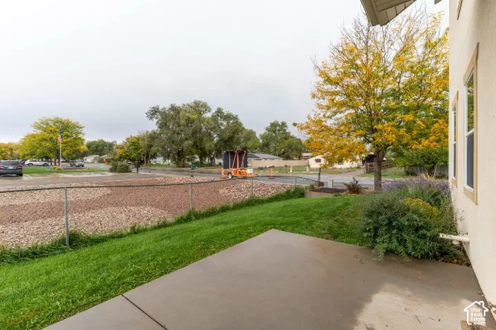 Concrete patio featuring a grass lawn, decorative gravel landscaping, and metal chain-link fencing