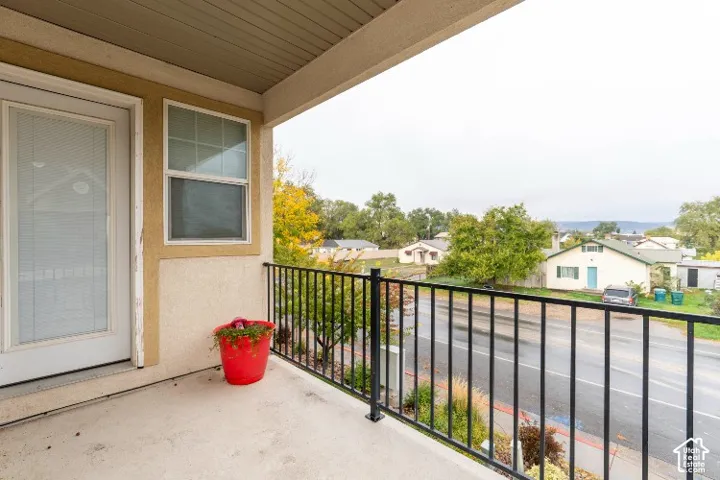 Covered balcony featuring concrete flooring, black metal railing, and stucco exterior walls