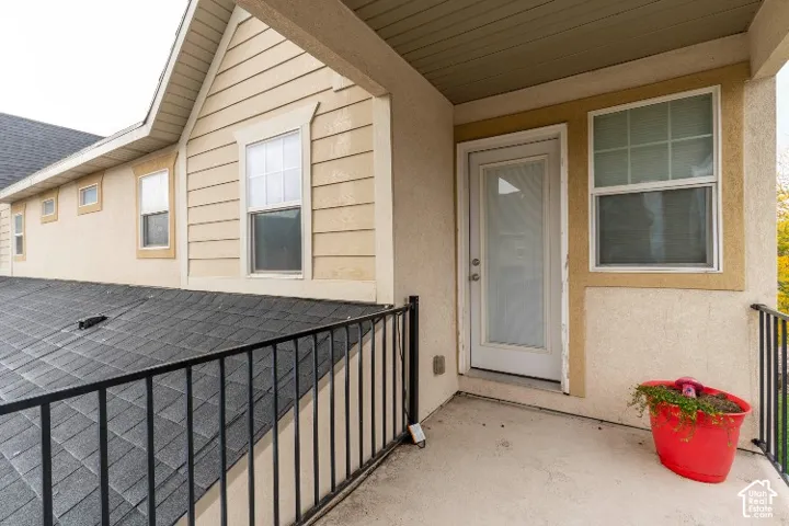 Balcony with concrete flooring, black metal railing, dual-tone stucco and horizontal lap siding exterior, and a glass-panel entry door