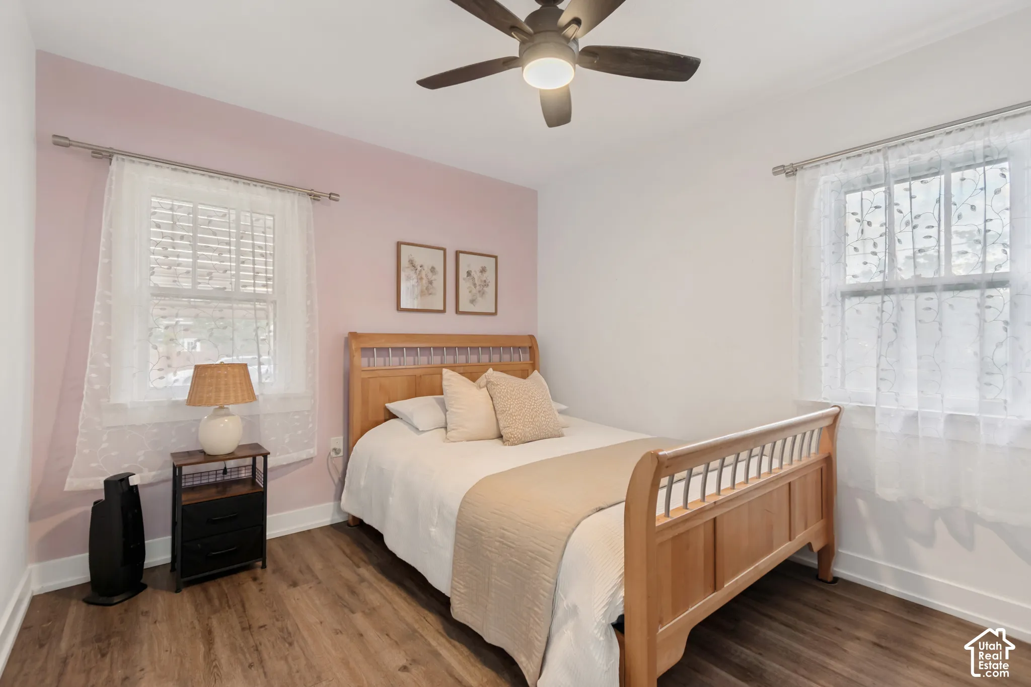 Room featuring wood-finish flooring, two double-hung windows, and a ceiling fan with integrated lighting