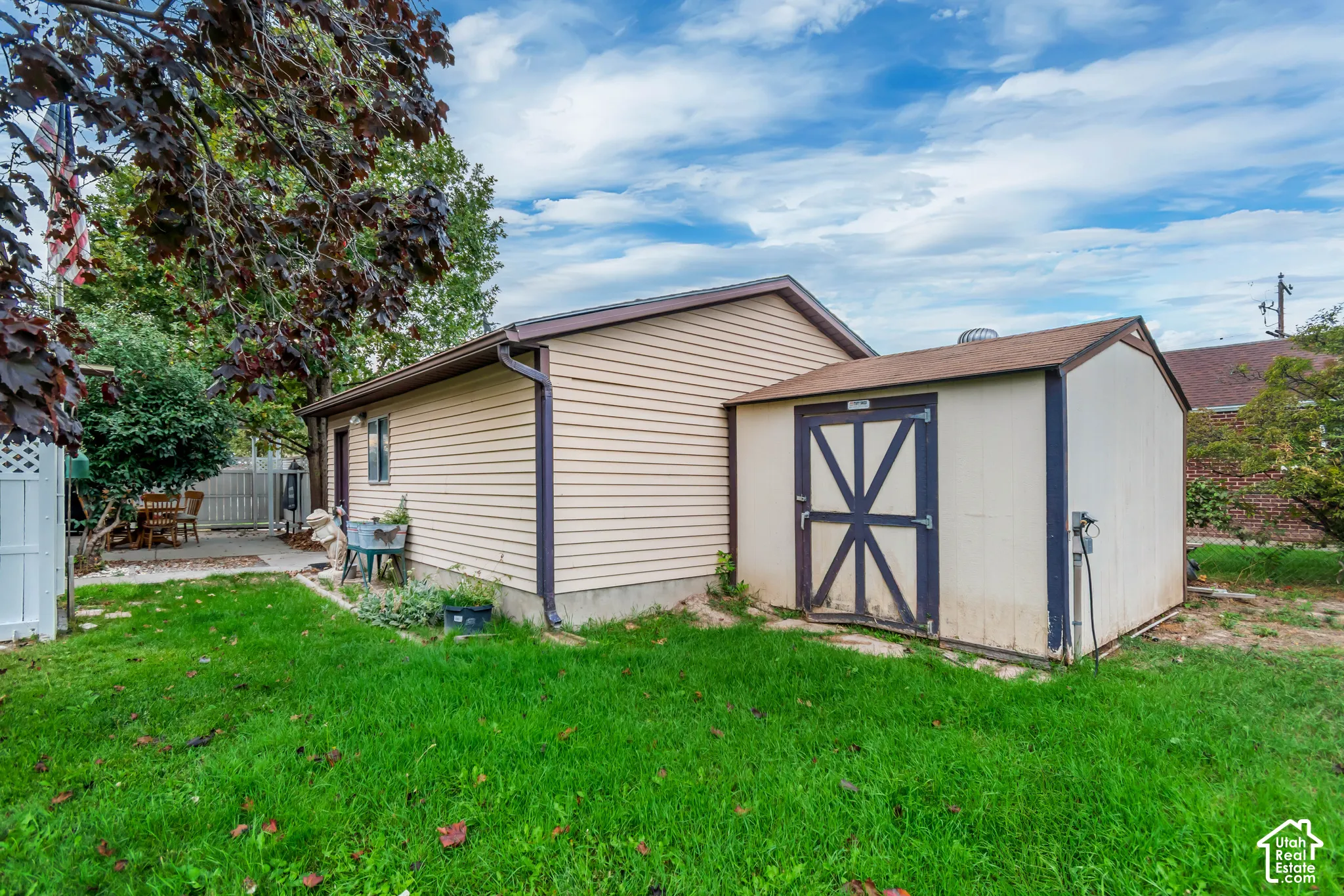 Exterior featuring vinyl siding, shingled roof, attached storage structure, and expansive lawn space