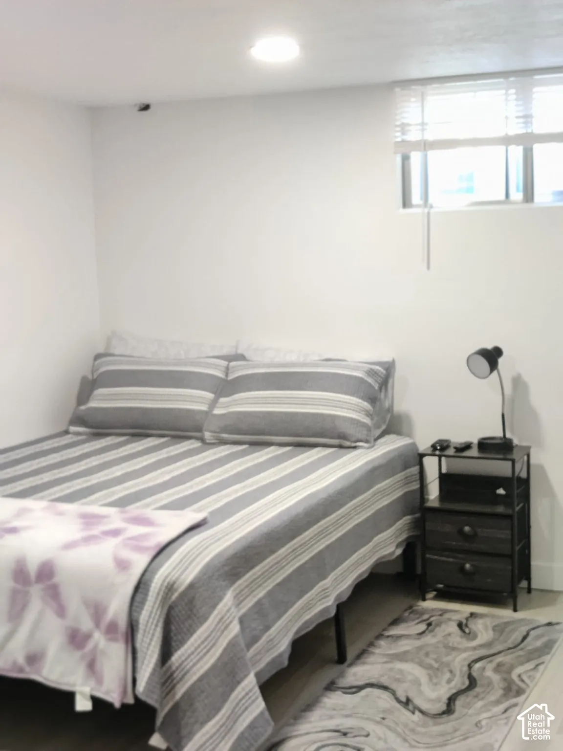 Neutral interior room featuring white walls, recessed ceiling lighting, and a high-set window with integrated blinds