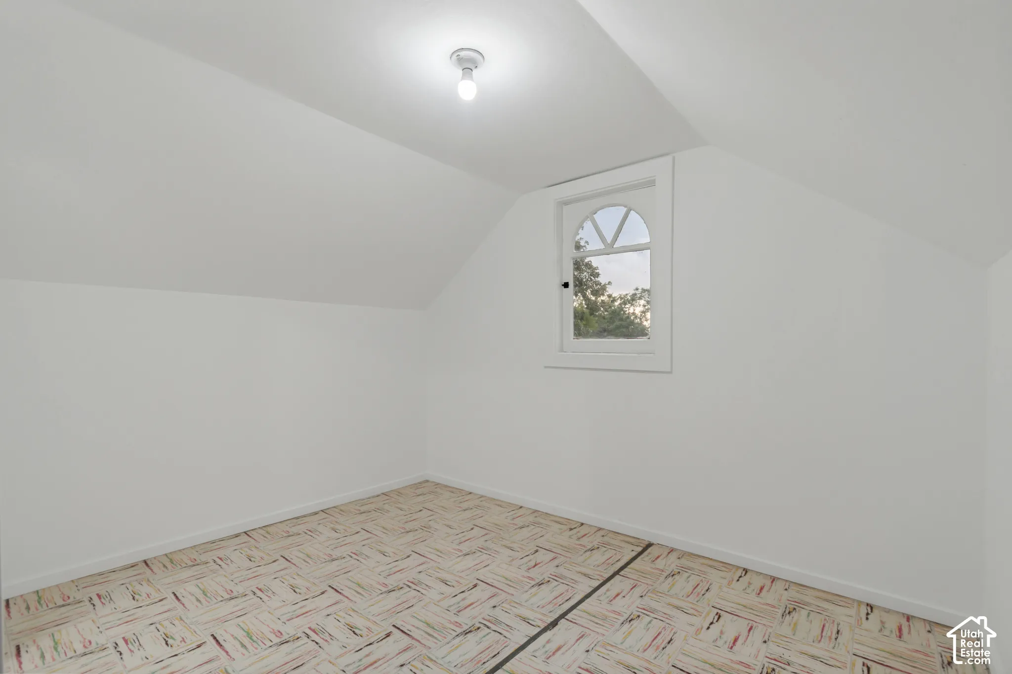 Sloped ceilings, arched window with divided lites, and parquet-style flooring