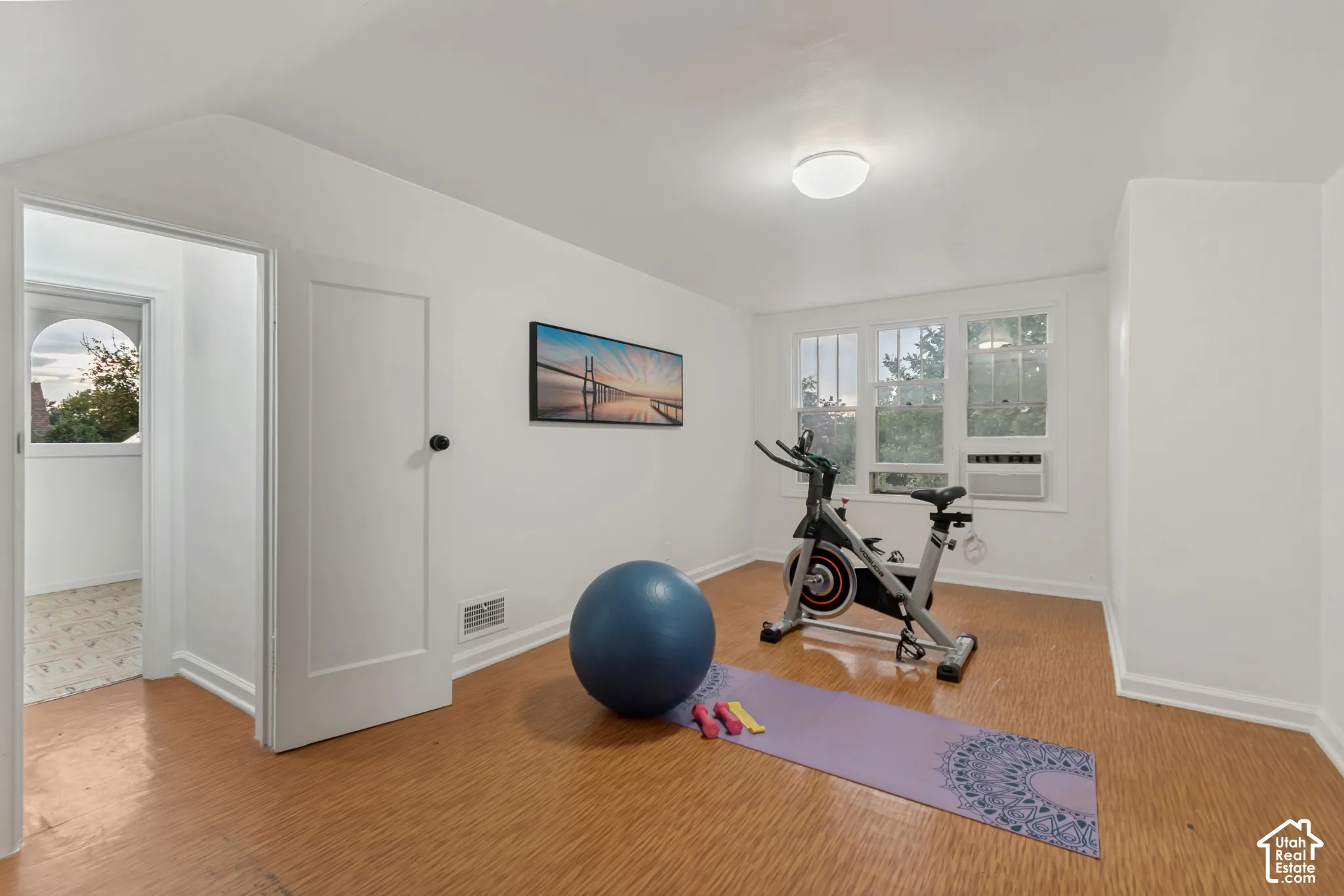Room with wood-finish flooring, white walls, and triple-pane window configuration featuring a built-in window air conditioning unit and ceiling-mounted dome lighting
