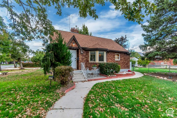 Brick exterior featuring a steeply pitched gable, shingle roofing, bay window, and concrete walkway
