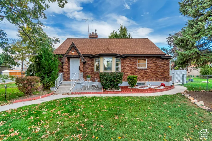 Brick exterior featuring a gabled entryway, bay window, shingled roof, and concrete walkway