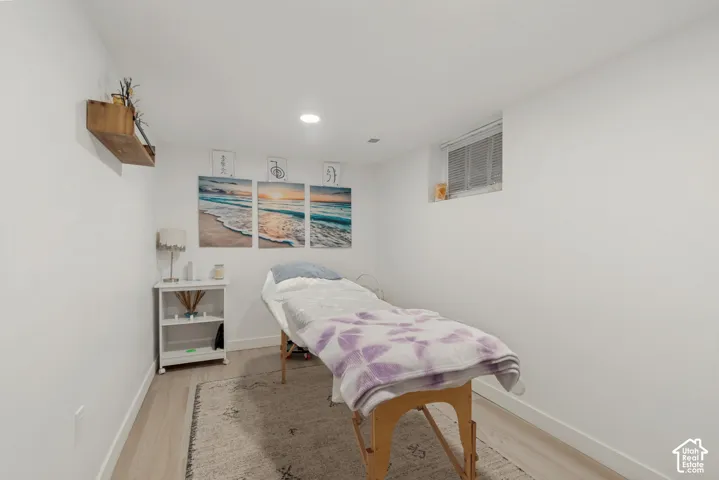 Interior room featuring wood-finish flooring, recessed lighting, and a wall-mounted wooden shelf