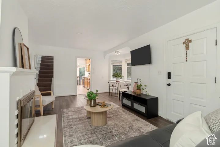 Living area featuring wood-finish flooring, a fireplace with a mantel, and a bay window