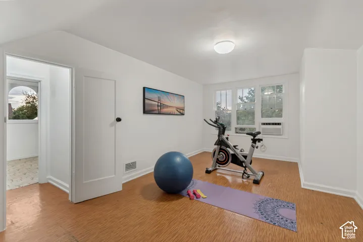 Room with wood-finish flooring, white walls, and triple-pane window configuration featuring a built-in window air conditioning unit and ceiling-mounted dome lighting