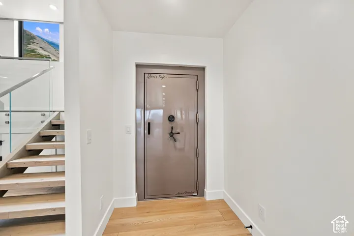 Built-in heavy-duty steel safe door, wood-finish flooring, and staircase with wood treads and glass panel railing