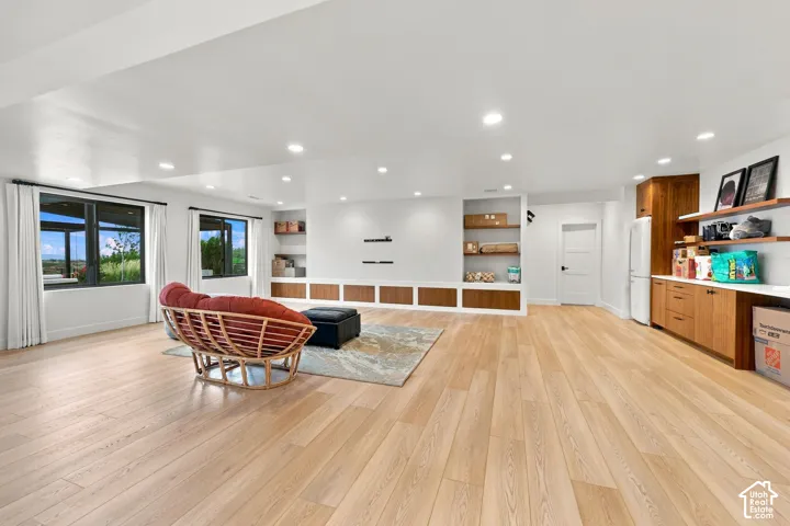 Spacious room featuring wood-finish flooring, recessed lighting, built-in wooden cabinetry, custom shelving, and expansive windows