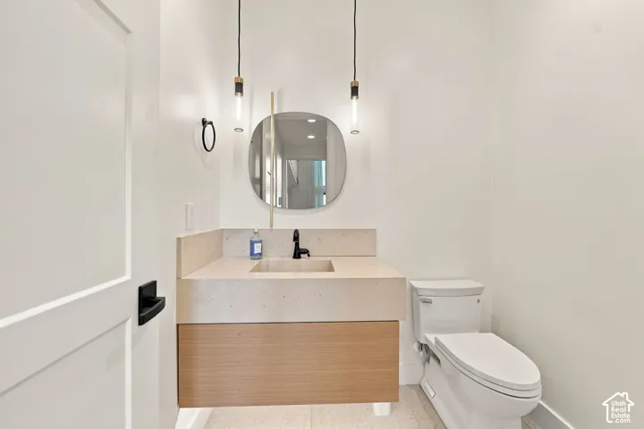 Floating wood-finish vanity with an integrated basin, stone-surface countertop, oval wall mirror, and dual pendant light fixtures