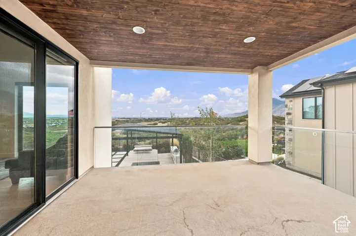 Covered balcony featuring a wood-plank ceiling, recessed lighting, and a glass-paneled railing