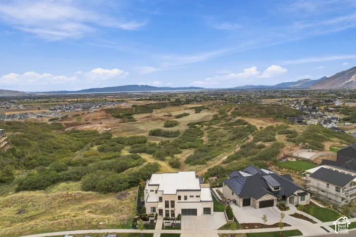 Aerial perspective featuring multi-story residential architecture with light-toned facades, flat rooflines, integrated multi-car garages, and panoramic mountain backdrop