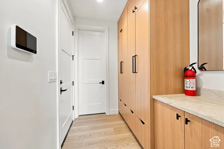 Full-height wood-finish cabinetry, stone countertop, wood-finish flooring, and matte black hardware