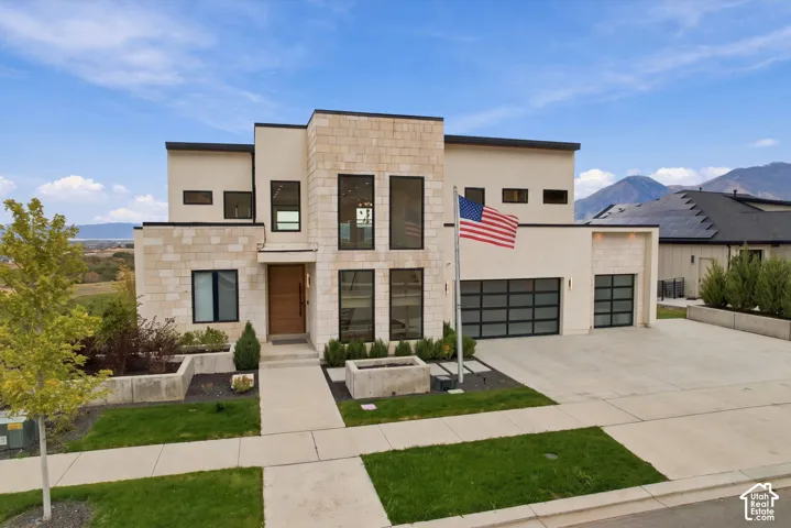 Contemporary exterior featuring a stone veneer facade, floor-to-ceiling windows, modern garage doors with frosted glass panels, and a concrete driveway